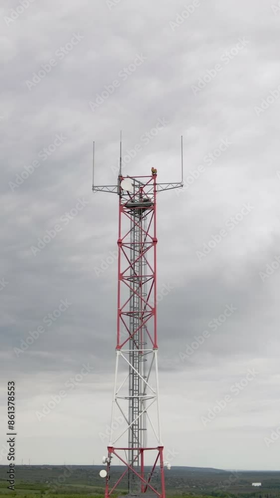 Vertical video. Mobile receiver and transmitter antenna tower, antenna tower building with the blue sky. Close-up of the antenna building or Communication antenna tower with the sky background Vertical video. Mobile receiver and transmitter antenna tower, antenna tower building with the blue sky. Close-up of the antenna building or Communication antenna tower with the sky background