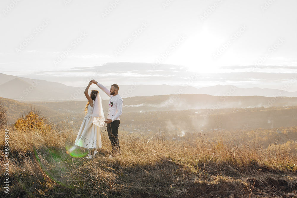 A bride and groom are dancing in a field with mountains in the background. Scene is romantic and peaceful A bride and groom are dancing in a field with mountains in the background. Scene is romantic and peaceful