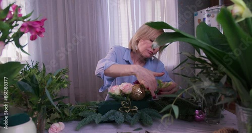 Professional woman florist takes care of seedlings in floral studio and looking at camera