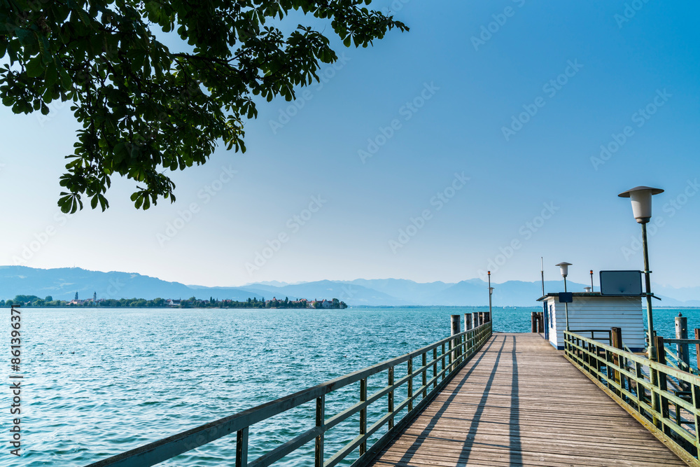 Germany, Landing stage for boats and ferry at lindau lindenhofpark public park with view to old town lindau island houses in summer with blue sky