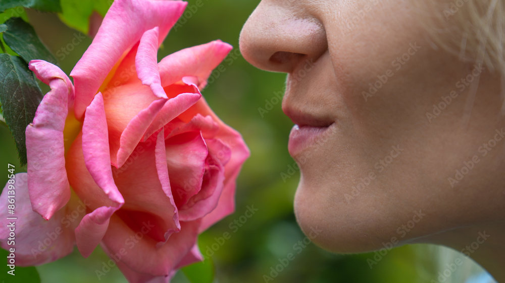 Scent of roses. Young blonde woman inhales the scent of a pink rose in the garden. Spring and summer. Perfumes and cosmetics. Scent of roses. Young blonde woman inhales the scent of a pink rose in the garden. Spring and summer. Perfumes and cosmetics.