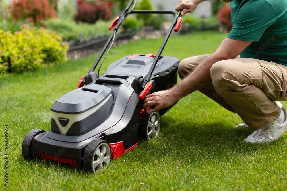 Man checking his lawn mower, cutting green grass on the backyard of his private house, cropped Man checking his lawn mower, cutting green grass on the backyard of his private house, cropped