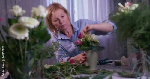 Professional woman florist creates a bouquet in a flower studio.