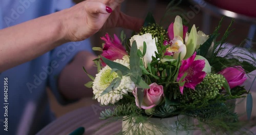 Female florist's hands remove extra petals from bud of flower. Close-up of basket full of spring pink flowers. Vertical video format