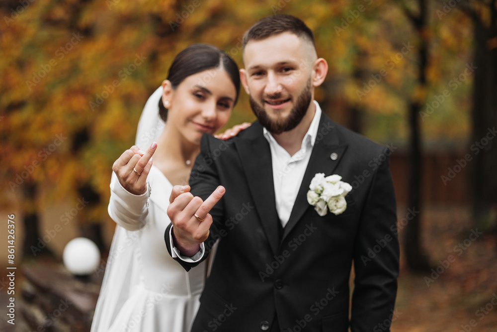 A bride and groom are posing for a picture with their hands up in the air, one of them giving a thumbs up A bride and groom are posing for a picture with their hands up in the air, one of them giving a thumbs up