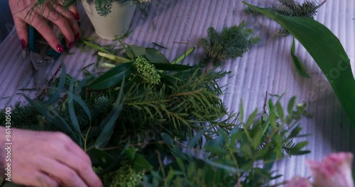 Female florist's hands remove extra petals from bud of flower. Close-up of basket full of spring pink flowers. Vertical video format