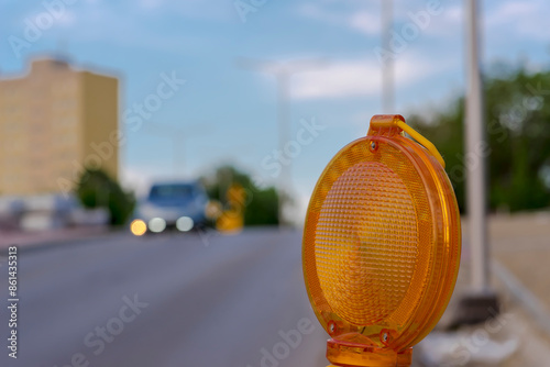 Budowa drogi - lampka ostrzegawcza na nowo wybudowanej drodze. Plac budowy dróg w mieście wśród bloków mieszkalnych pomarańczowe światło ostrzegawcze. photo