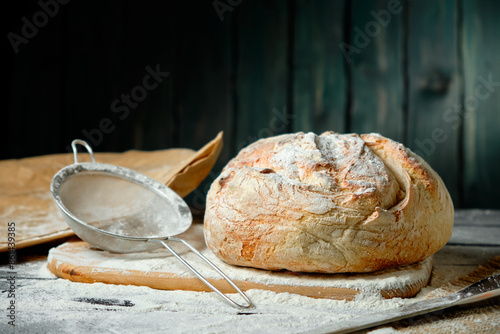 fresh loaf of bread sprinkled with flour on a wooden background photo