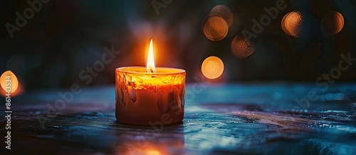 Candle burning brightly against a dark backdrop with copy space image, evoking feelings of sorrow.