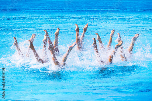 Artistic swimmers team performing synchronized legs choreographed movement in the swimming pool