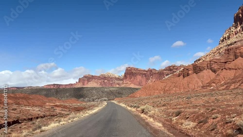 Point of view POV driving shot of the scenic drive in Capitol Reef National Park, Utah on a sunny day. Red rock formations and cliffs tower over the road, with stunning views of the desert - USA