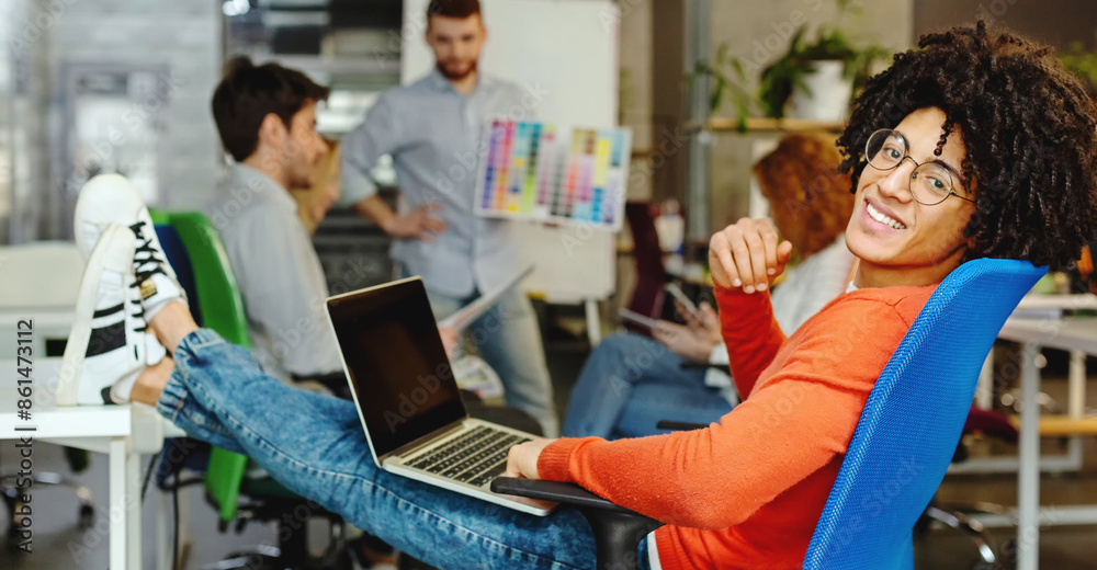 Smiling man enjoying work in modern comfortable cozy co-working space, relaxing while his friend discussing project, panorama Smiling man enjoying work in modern comfortable cozy co-working space, relaxing while his friend discussing project, panorama