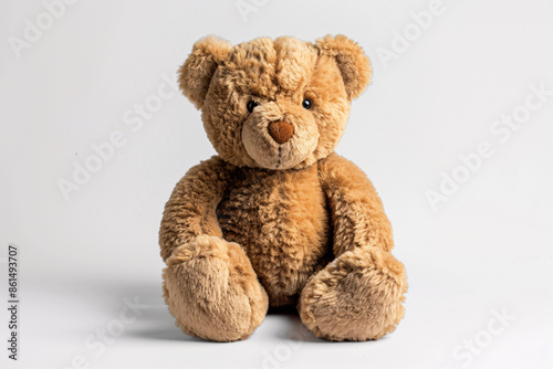 a brown teddy bear sitting on a white surface
