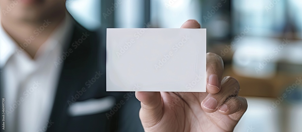 A close-up picture displaying a hand grasping a blank business card in an office setting with an empty space for copy in the image. A close-up picture displaying a hand grasping a blank business card in an office setting with an empty space for copy in the image.