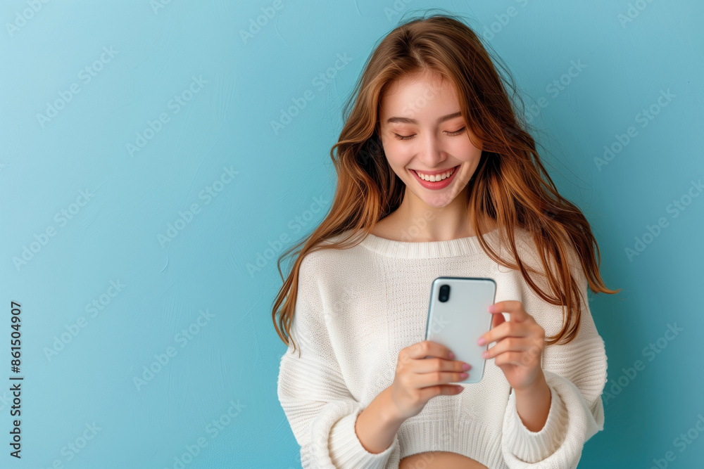 pretty woman smiling happily while reading message on her smart phone on isolate blue background pretty woman smiling happily while reading message on her smart phone on isolate blue background