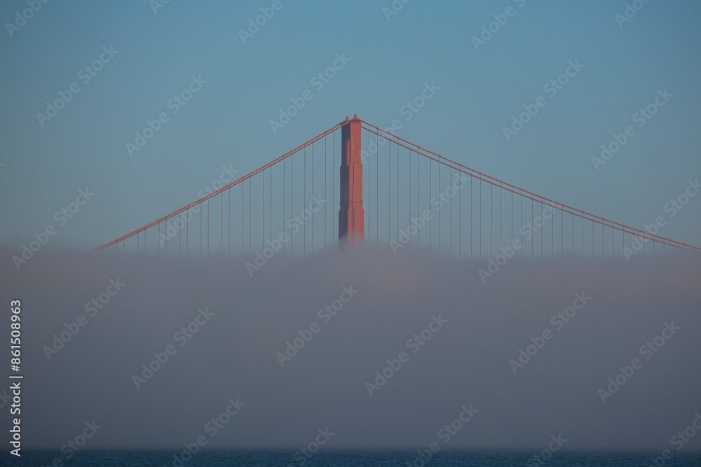World famous red steel suspension bridge in San Francisco port entrance with Golden Gate State park nature lands hidden in cloud mist fog bank with clear sky pilars World famous red steel suspension bridge in San Francisco port entrance with Golden Gate State park nature lands hidden in cloud mist fog bank with clear sky pilars