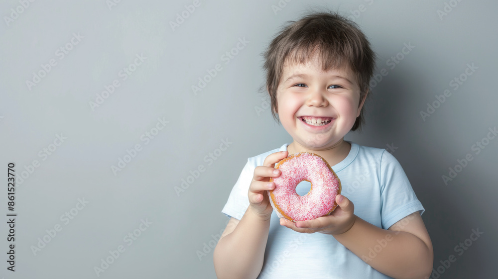 Smiling child holding a pink frosted donut against a gray background. Joyful moment capturing sweetness and happiness Smiling child holding a pink frosted donut against a gray background. Joyful moment capturing sweetness and happiness