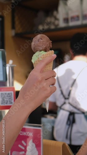 A woman's hand takes an ice cream cone from a seller. the girl holds in her hand a cone with melted ice cream with topping and it flows down her hand. ice cream flows down your hand. Close-up. Macro. 