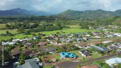 Houses in nature in Kauai Poipu Koloa. Drone Flying Over Beautiful neighbourhood in Hawaii with Mountain Range in Distance. Single family homes from above in green natural environment on sunny day