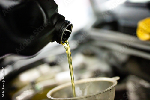 Car mechanic replacing and pouring fresh oil into engine at maintenance repair service station, closeup