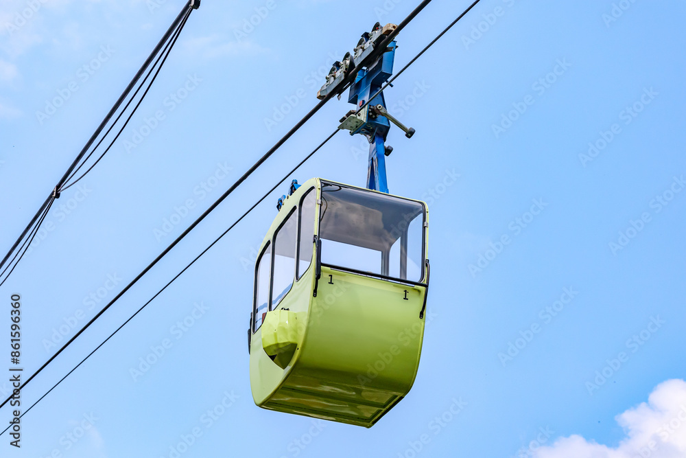 Empty green cabin hanging on cables of cable car against blue sky background, view from a bottom perspective, sunny spring day in Cologne, Germany Empty green cabin hanging on cables of cable car against blue sky background, view from a bottom perspective, sunny spring day in Cologne, Germany