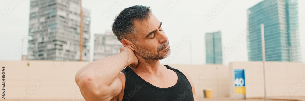 Close-up of mature man stretching his neck muscles while standing on the beach in the morning Close-up of mature man stretching his neck muscles while standing on the beach in the morning