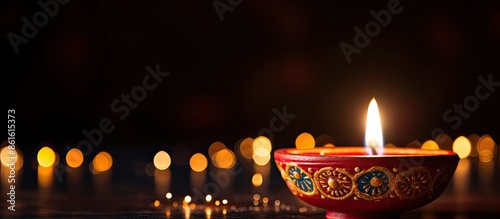 A traditional oil lamp, a clay diya candle, is glowing in celebration of Diwali, a Hindu festival of lights, set against a dark background with copy space image. photo