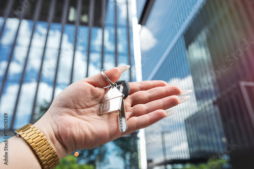 Real estate agent with house key against background of skyscrapers in city