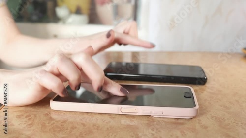 Close up of woman's hands quickly presses her fingers on two smartphone screens.