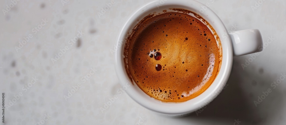 Close up of a cup with espresso cream, showing a beautiful texture, placed on a white table with an aromatic medium-dark Arabica coffee copy space image.