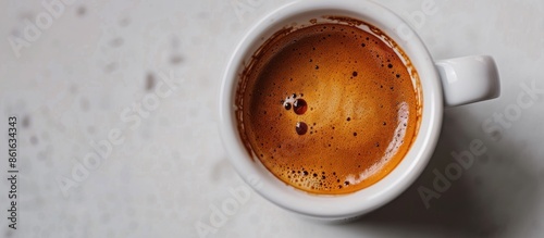 Obraz na płótnie Close up of a cup with espresso cream, showing a beautiful texture, placed on a white table with an aromatic medium-dark Arabica coffee copy space image. w salonie