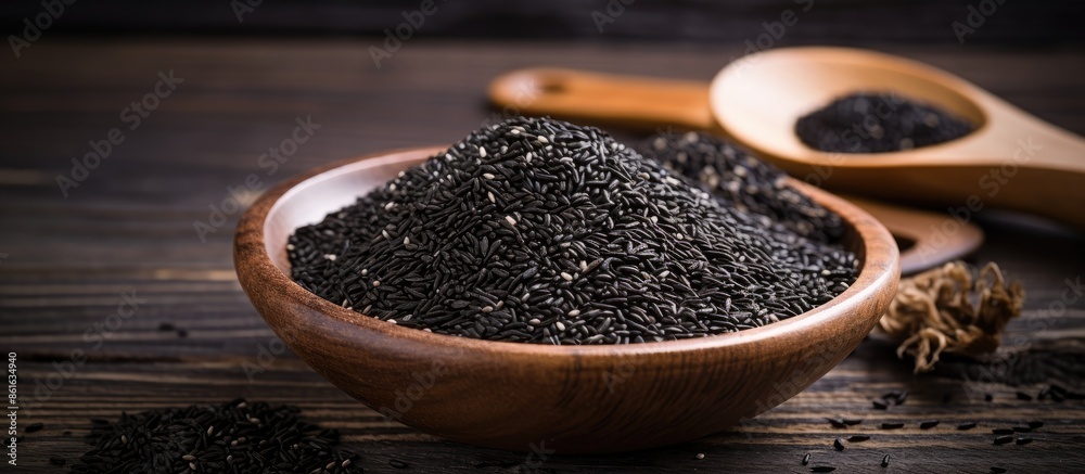 Black sesame seeds spice arranged in a pile on a black wooden surface with an available area for additional content, like a copy space image. Black sesame seeds spice arranged in a pile on a black wooden surface with an available area for additional content, like a copy space image.