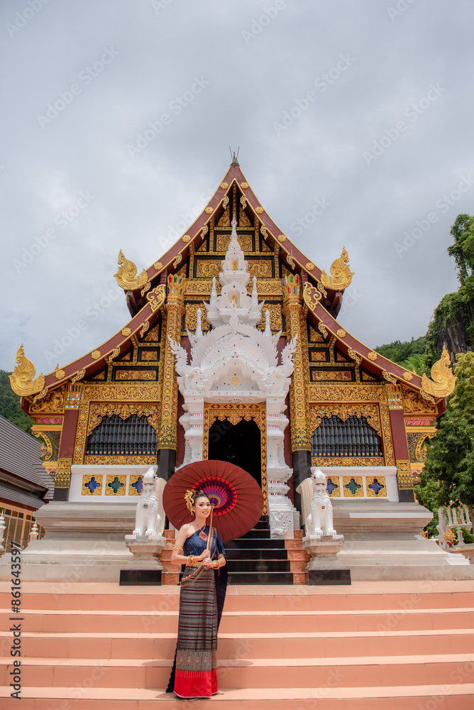 Fototapeta premium Woman wearing Thai dress visits beautiful temple in Thailand.
