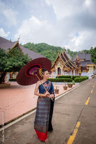 Woman wearing Thai dress visits beautiful temple in Thailand.
