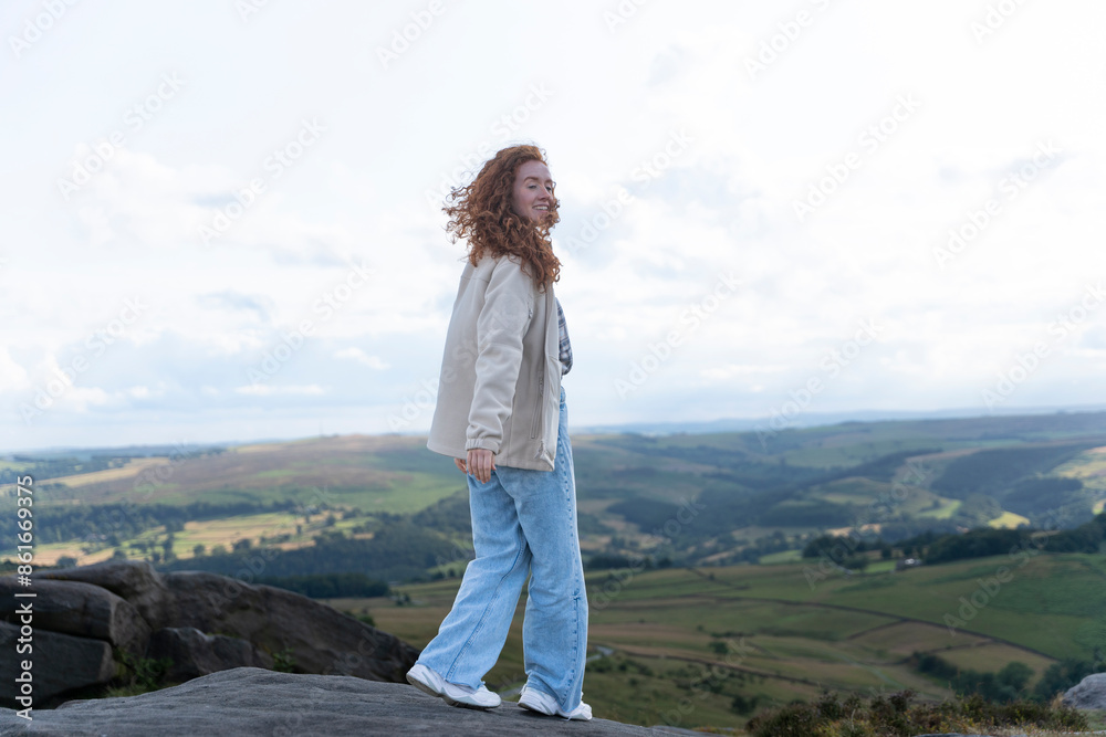Woman With Red Hair Stands on Rocky Outcrop With View of Rolling Hills in the Peak District Woman With Red Hair Stands on Rocky Outcrop With View of Rolling Hills in the Peak District