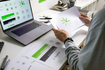 Close-up shot of a graphic designer making notes on logo designs, using tablet and laptop, designing logos, and showcasing the corporate identity and logo design process.