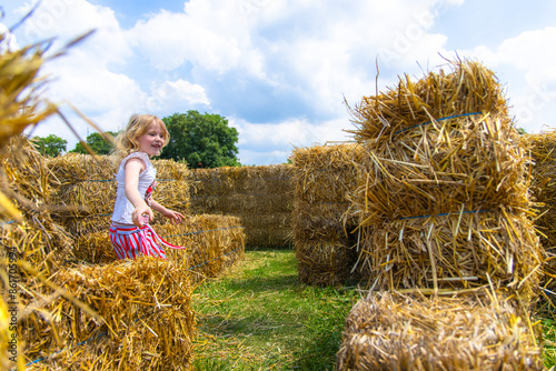 Young Girl Playing in Hay Bale Maze on Sunny Day