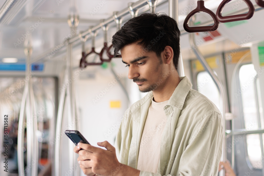 Portrait of young Indian man passenger traveling and using his smartphone in the metro or subway train. Metro and Public transportation concept. Portrait of young Indian man passenger traveling and using his smartphone in the metro or subway train. Metro and Public transportation concept.
