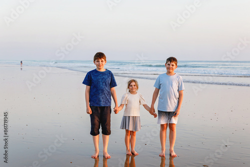 Three children, happy siblings on ocean beach at sunset. happy family, two school boys and one little preschool girl. Brothers and sister having fun, Spain, Costa del Sol photo