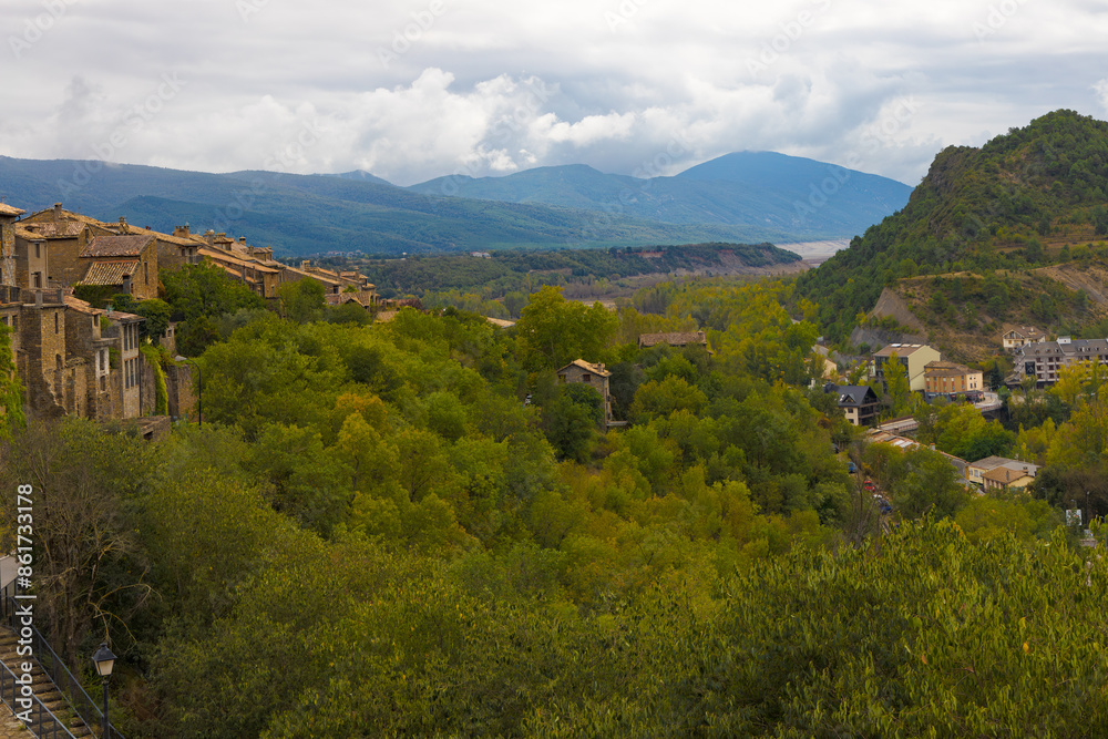 Una vista panorámica desde las murallas del castillo de Ainsa, Aragón, España, muestra un paisaje impresionante de colinas verdes y montañas bajo un cielo nublado. Una vista panorámica desde las murallas del castillo de Ainsa, Aragón, España, muestra un paisaje impresionante de colinas verdes y montañas bajo un cielo nublado.