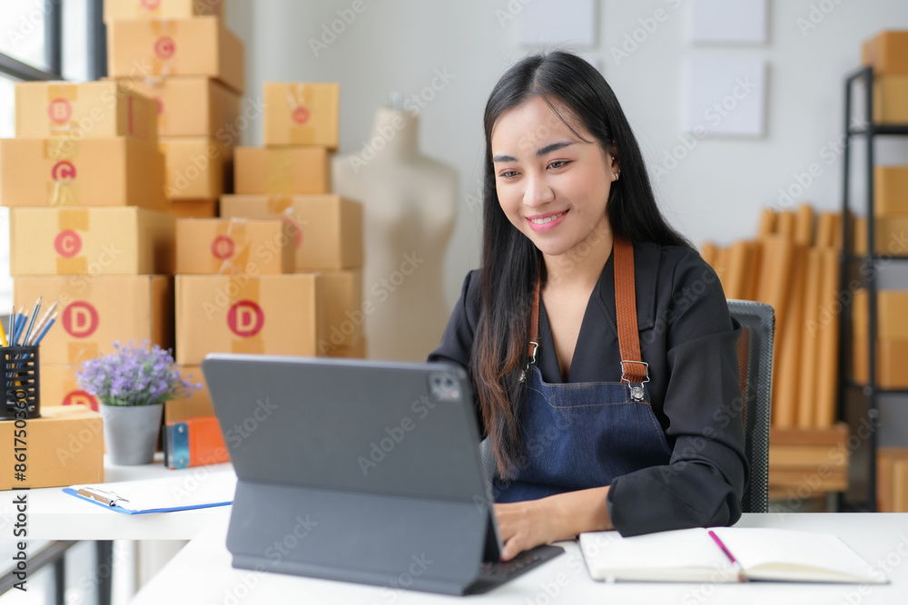 Asian sme business woman using tablet and smiling while working in her home office Asian sme business woman using tablet and smiling while working in her home office