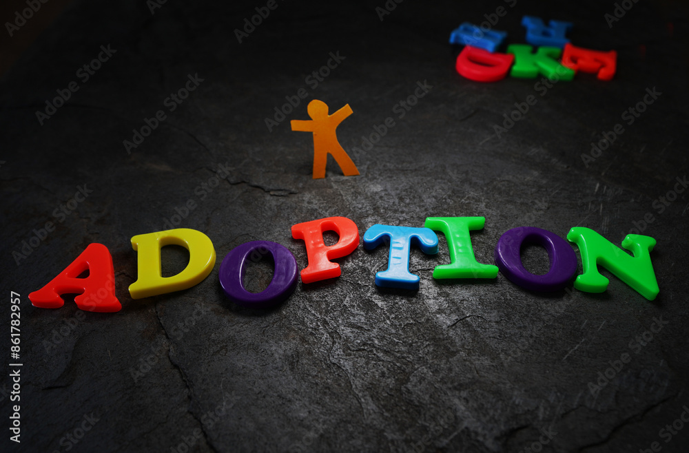 Adoption spelled in colorful play letters with paper cutout child on textured background Adoption spelled in colorful play letters with paper cutout child on textured background