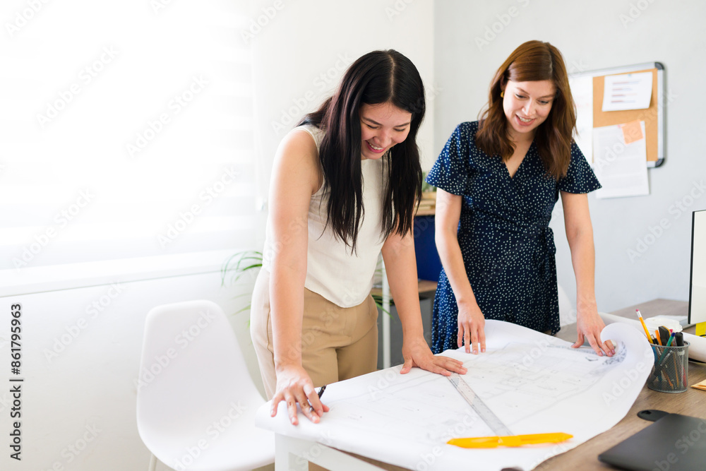 Two female entrepreneurs discussing and planning over blueprints in a bright, modern startup office environment, showcasing teamwork and partnership Two female entrepreneurs discussing and planning over blueprints in a bright, modern startup office environment, showcasing teamwork and partnership