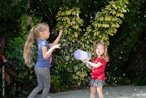 two kids playing with a bubble gun. Bubble machine best toy for small kids. Summer fun activities for kids.