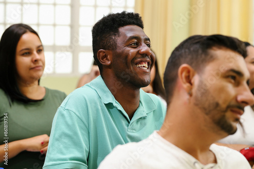 Selective focus on a happy adult black student smiling with his classmates.