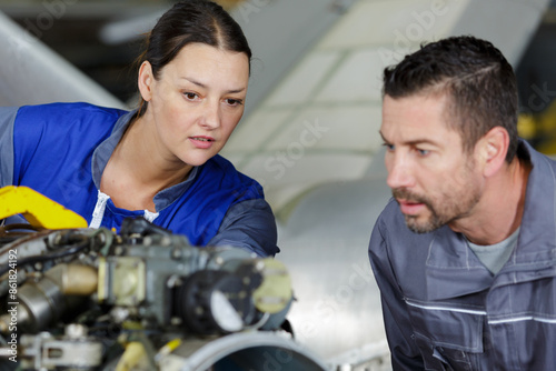 man and woman working on an airplane engine