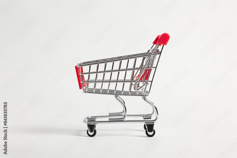 A small empty shopping cart with red handles and wheels against a plain white background
A small empty shopping cart with red handles and wheels against a plain white background