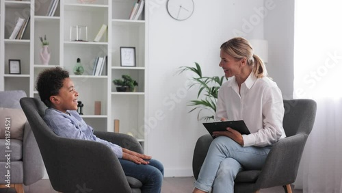 Kids psychology concept. Professional blonde woman therapist communicating with happy little boy patient, talking during personal consultation at office.