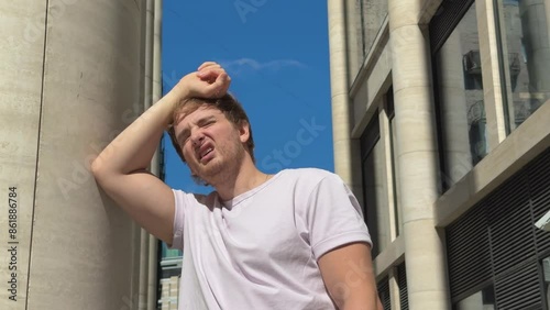 tired sick exhausted man is suffering from hot Summer heat stroke, sunshine, hot weather day, sweaty and thirsty, high temperature. Feeling unwell, unhealthy