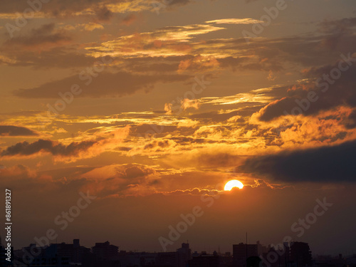 都市の夜明け。雲の隙間から太陽が顔を出す